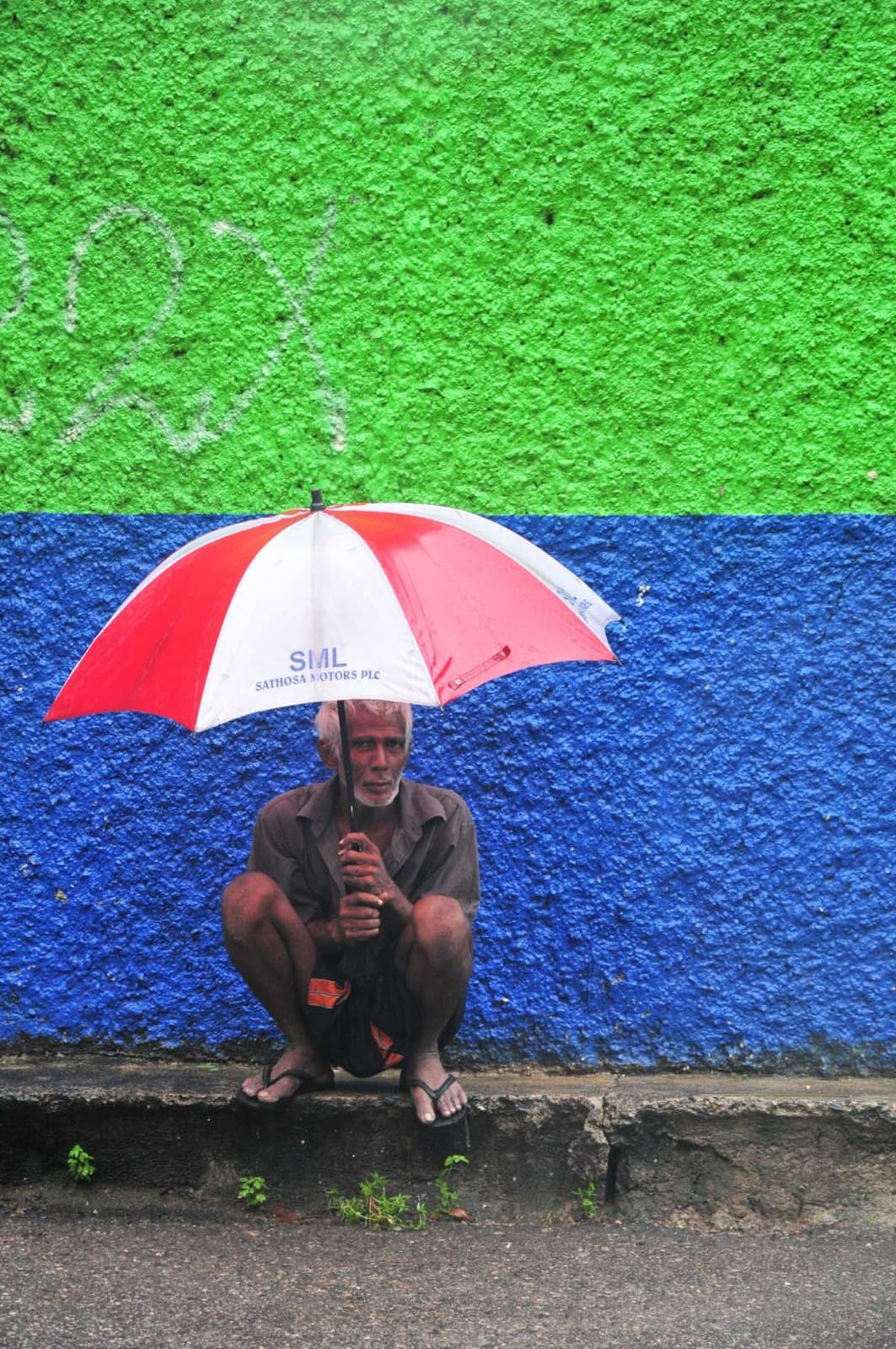A man taking shelter from rain under an awning